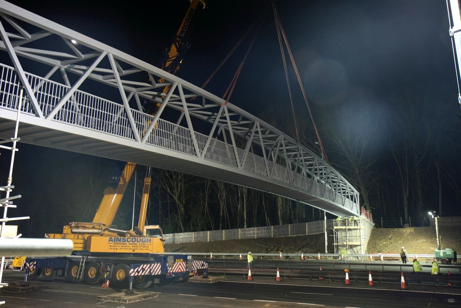 Steel footbridge being lifted into place at night